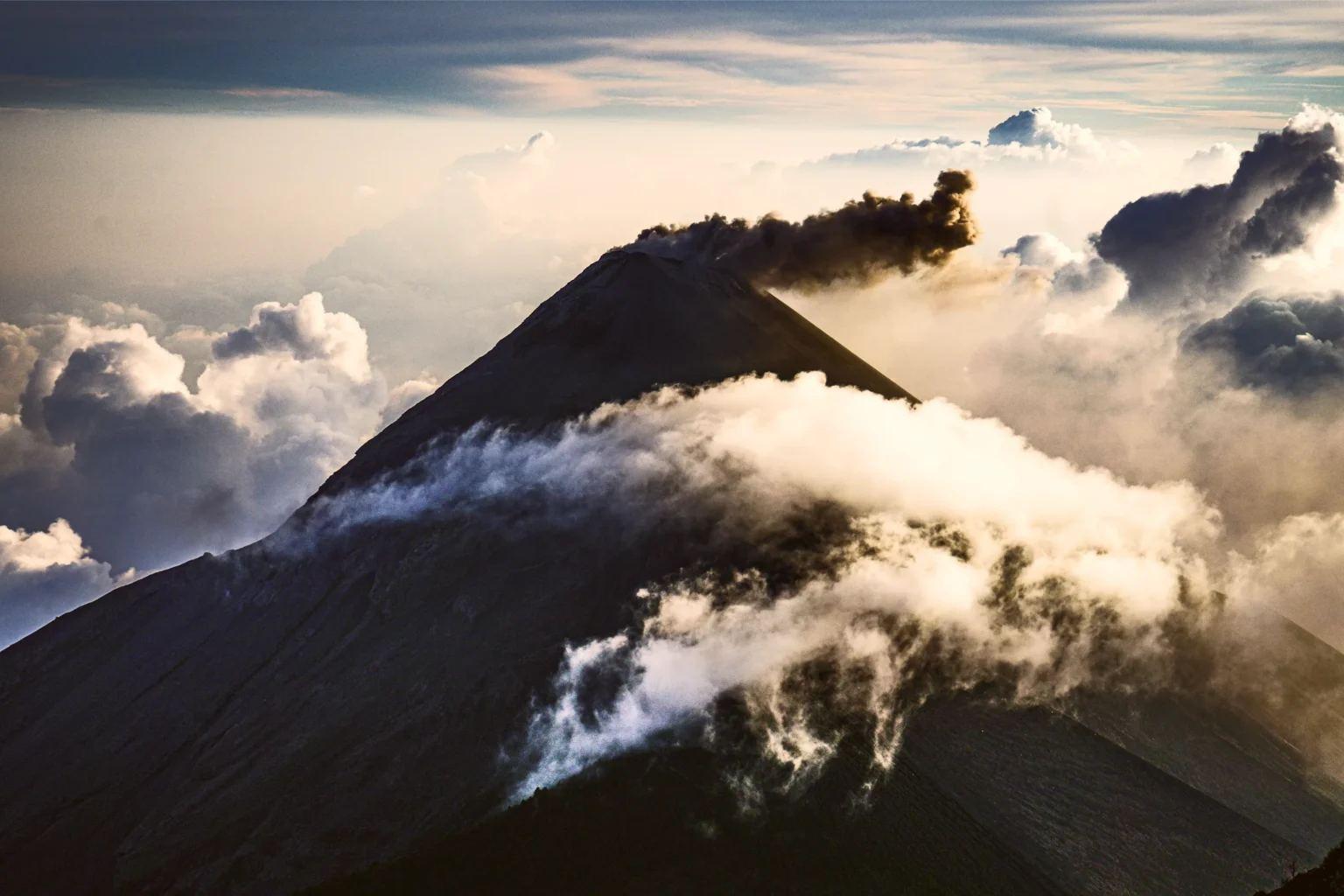 Cumbre del Volcán de Fuego entre nubes al amanecer.